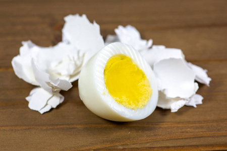 特写一个 (完整) 和半鸡蛋破裂的棕色壳揭示黄色蛋黄与蛋清,白色背景