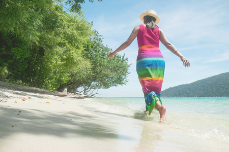 一个美丽的无忧无虑的女人在海滩上放松享受她的太阳衣服自由穿