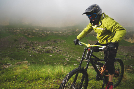 一个骑着山地自行车的戴着山车头盔的男人在多云的天气里绕着美丽的大自然兜风。下坡