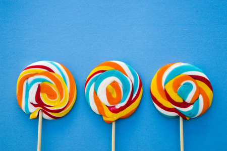 彩色棒糖在蓝色背景 糖果上的红色 白色和蓝色条纹 最小的概念 糖果店系列照片 正版商用图片0qs9g9 摄图新视界