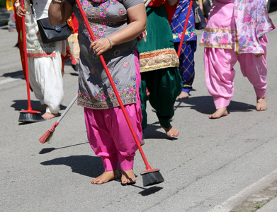 穿着传统衣服的锡克赤脚妇女在宗教庆典上用扫帚清洁街道