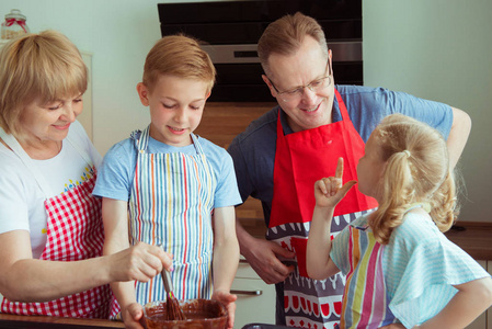 快乐的祖父母与他们的孙子们一起在现代厨房里准备巧克力松饼的乐趣