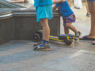 关闭孩子的腿和踢滑板车在一个夏天的一天在街上