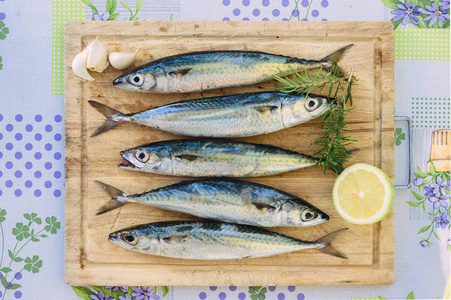 生鲭鱼, 有大蒜的爪子和木盘子上的柠檬.鲜鱼照片