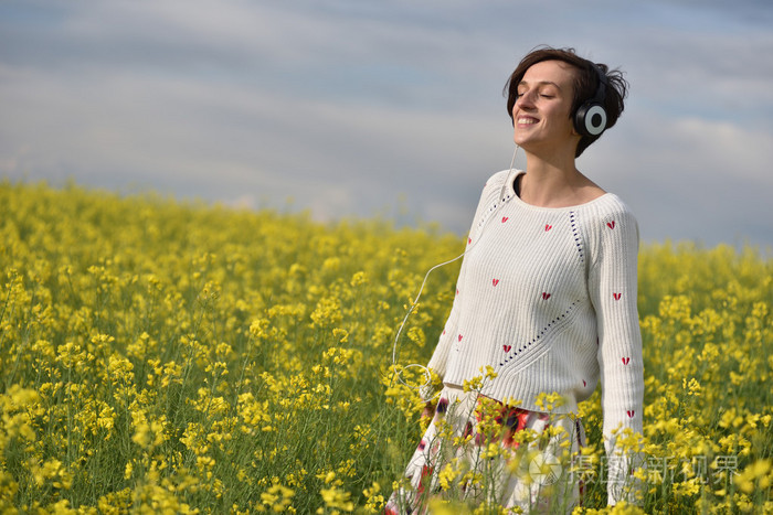 年轻快乐的女人在户外的耳机听音乐