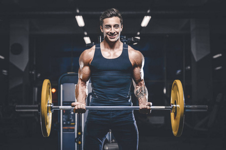 英俊的年轻适合肌肉的白种人模型外观锻炼训练在健身房获得重量抽肌肉