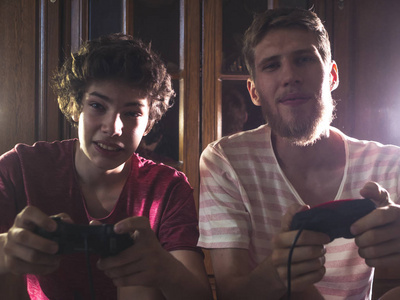 两个男青少年感到快乐的情绪, 而赢得视频游戏在家中的夜晚色调