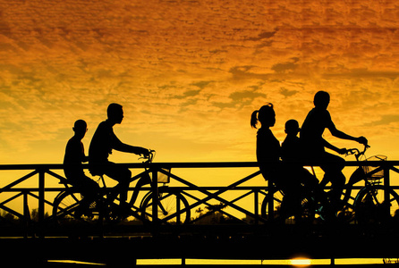 骑自行车的人在桥上在日落时的剪影