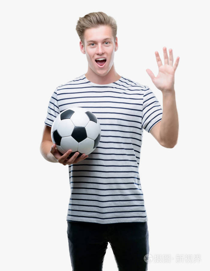 年轻英俊的金发男子举行足球非常高兴和兴奋, 优胜者表达庆祝胜利尖叫