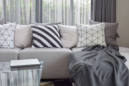 淡灰色的沙发上，用不同模式在现代生活的角落里的枕头