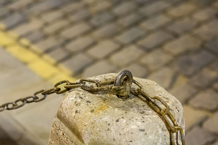 铁链生锈钩到水泥基座上的城市地区铺路石模糊背景