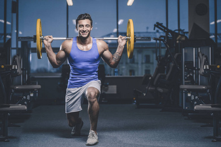 英俊的年轻适合肌肉的白种人模型外观锻炼训练在健身房获得重量抽肌肉