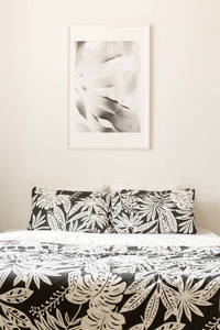 黑色和白色海报在床上与图案的垫子在最小的卧室内部。真实照片