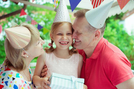 快乐祖父母的肖像庆祝生日与他们漂亮的小孙女在五颜六色的装饰露台