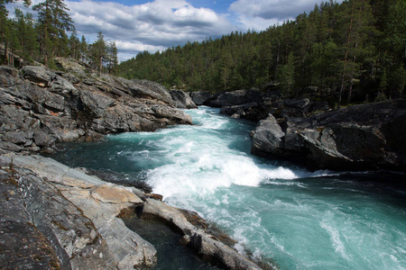 在挪威的岩石和森林里, 一条暴风雨般的小河流过, 清澈透明的蓝水