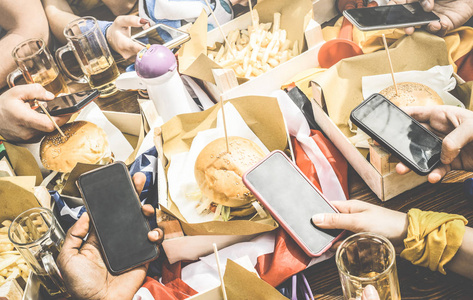 多元文化的朋友在餐厅在食物运动酒吧使用智能手机的多种族人们手里技术成瘾概念   复古的智能手机拥有乐趣组对比筛选器图片