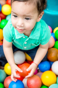 可爱的宝宝男孩穿着绿松石 t 恤玩彩色塑料球射角从