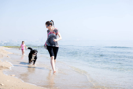幸福的家庭，在海滩上玩狗