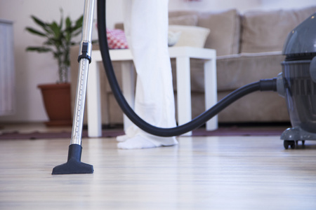 女人的密切联系腿真空吸尘器清理地板在家里