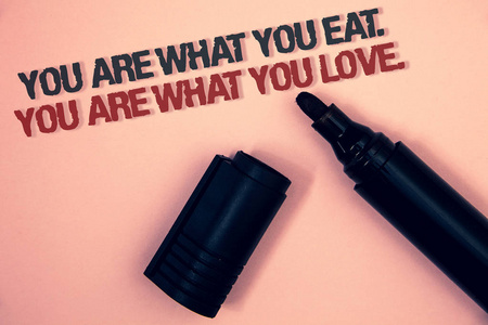 显示你吃东西的文字符号。你是你所爱的人。概念照片开始吃健康食品粉红色平台黑色和红色信息一角打开黑色标记