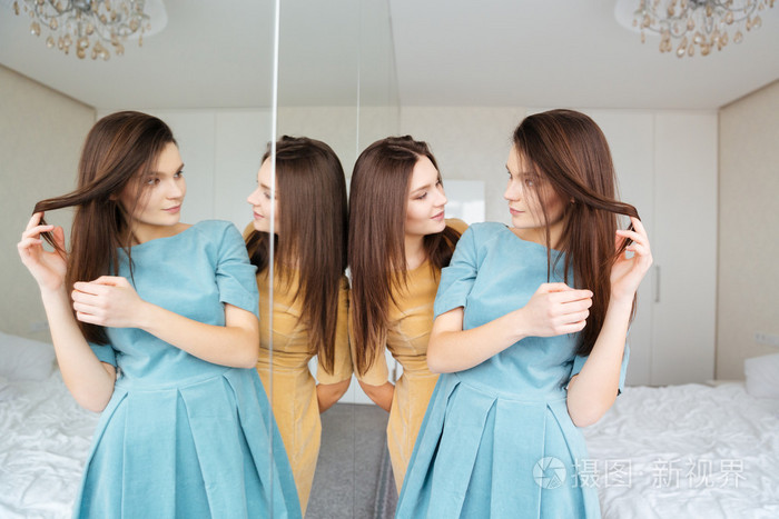 两姐妹双胞胎站，看着镜子