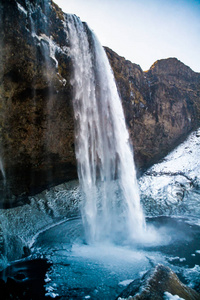 冬天, 冰岛美丽的 Seljalandsfoss。冰冻美丽的瀑布 Seljalandsfoss 在冬日的日出灯光下, 倒影在河中