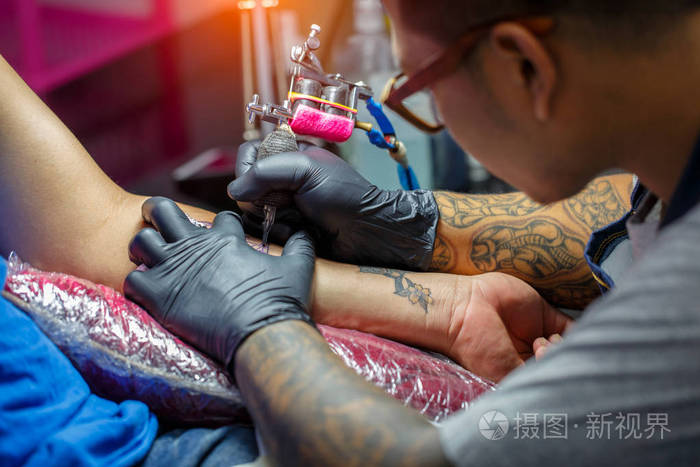 关闭了纹身艺术家演示涂成黑色纹身的过程.