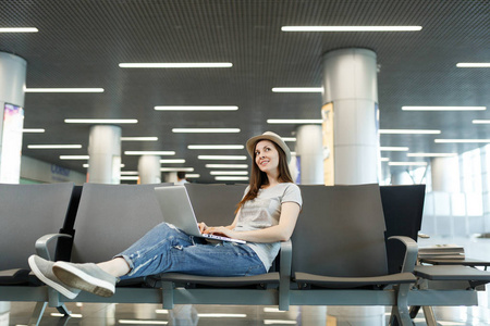 年轻的梦幻旅行者的旅游妇女在笔记本电脑上, 查找, 等待在大堂大厅在国际机场。周末出游的旅客出国旅行。航空旅行, 飞行旅途概念