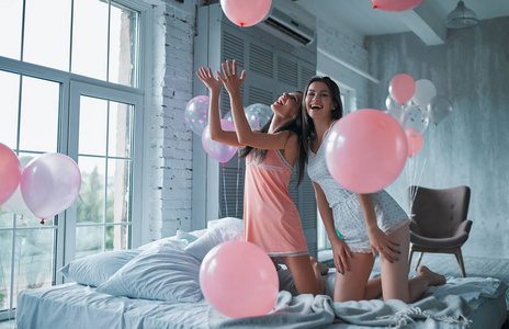 两个年轻漂亮的女人在卧室里玩得很开心。女孩睡衣派对
