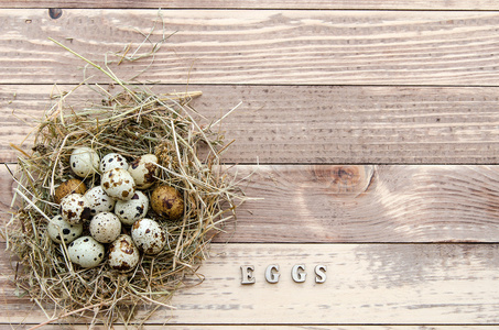 鹌鹑蛋在稻草窝在旧木桌背景。复古怀旧风格
