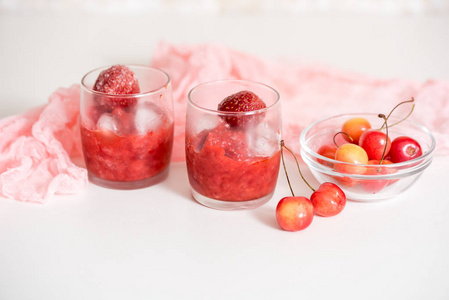 两杯樱桃果盘, 樱桃在盘子上, 餐巾上有粉红色的木质背景。选择性聚焦