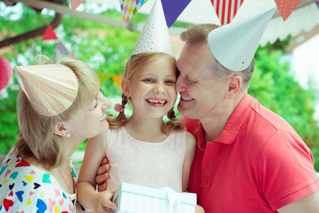 快乐祖父母的肖像庆祝生日与他们漂亮的小孙女在五颜六色的装饰露台