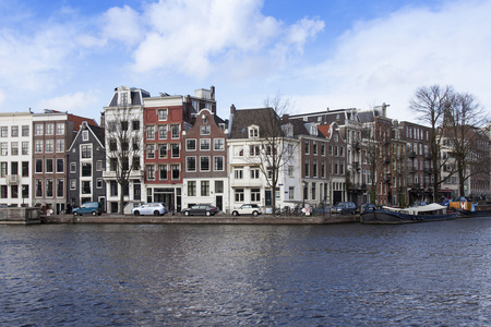 阿姆斯特丹，荷兰在 2016 年 3 月 29 日。典型的城市景观，在春天的下午。阿姆斯特尔河路堤的建筑群