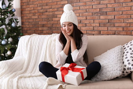 漂亮的年轻女子在帽子与礼品盒在家里。圣诞庆典