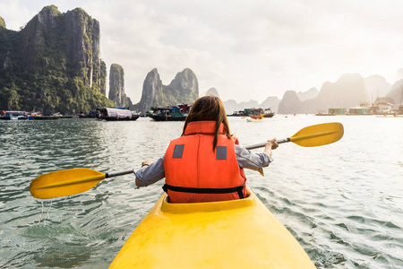 划皮艇在热带海湾的年轻女人旅行者