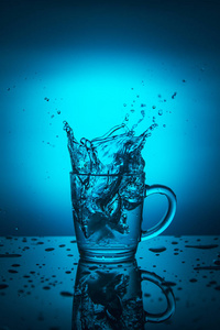 蓝色背景下杯中溅出的水