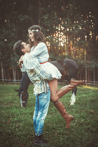 年轻和幸福的情侣在草地上抱着马