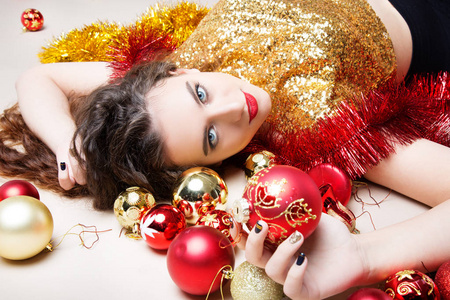 年轻漂亮的女孩，穿着黄金圣诞球和红色圣诞玩具