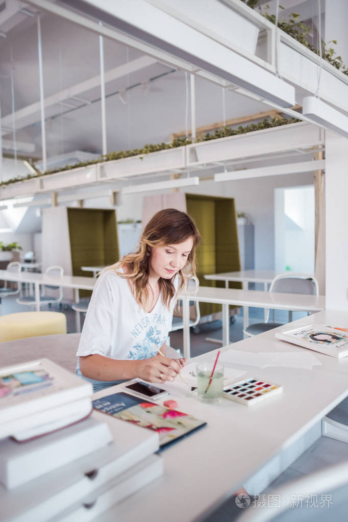艺术家在画室画一幅画.美丽的女孩在白色的内饰油漆