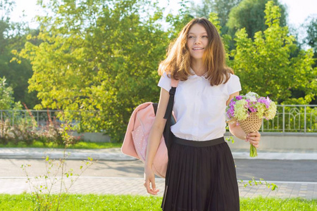 回到学校。快乐的少女第一天上学, 带着背包, 花。复制空间