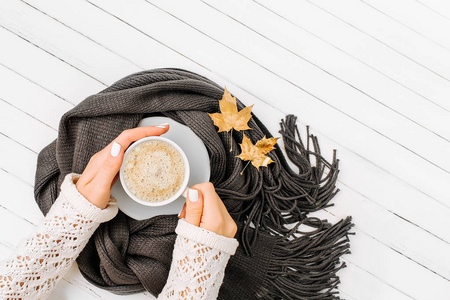 女人的手拿着一杯咖啡裹在木质的围巾上。秋季或冬季的概念。平躺, 顶部视图