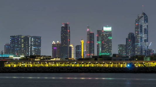现代迪拜城市天际线 timelapse 在夜间与照亮的摩天大楼在水面上。从 Daria 岛到迪拜市中心和商务海湾的景色