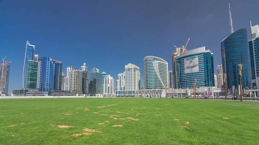 全景 timelapse hyperlapse 商务海湾和迪拜市中心地区的视野。现代摩天大楼, 绿草和蓝天