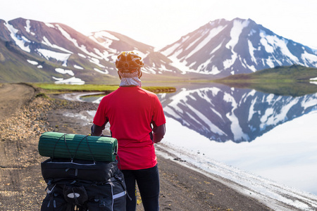 快乐骑自行车上的湖和雪的山，在冰岛的背景