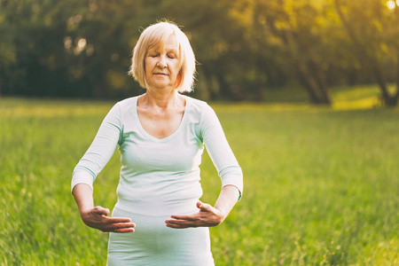 老年妇女在大自然中喜欢锻炼太极。图像是故意色调
