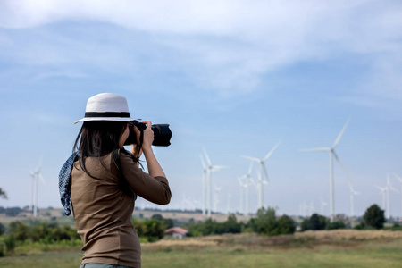 风力发电机组中拿着照相机的妇女摄影师采取