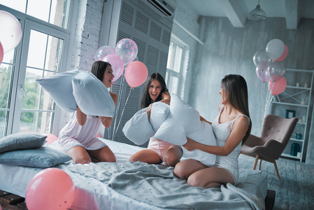 女孩睡衣派对在床上跳跃照片