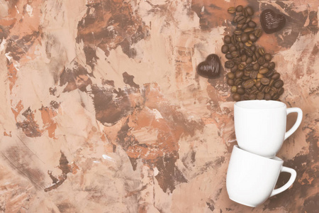 白色杯子里的咖啡充满咖啡豆和巧克力棕色背景上心的形式。顶视图，复制空间。食品背景。色调