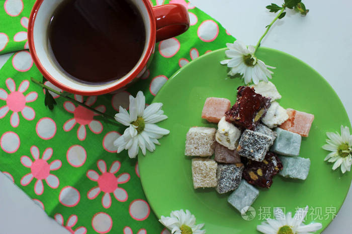秋天舒适。早餐与热茶在红色杯子, 土耳其乐趣和新鲜甘菊在绿色背景。顶部视图