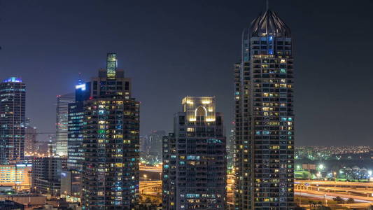 迪拜码头在夜间 timelapse, 闪闪发光的灯光和最高的摩天大楼。照亮的塔和交通在路在背景上
